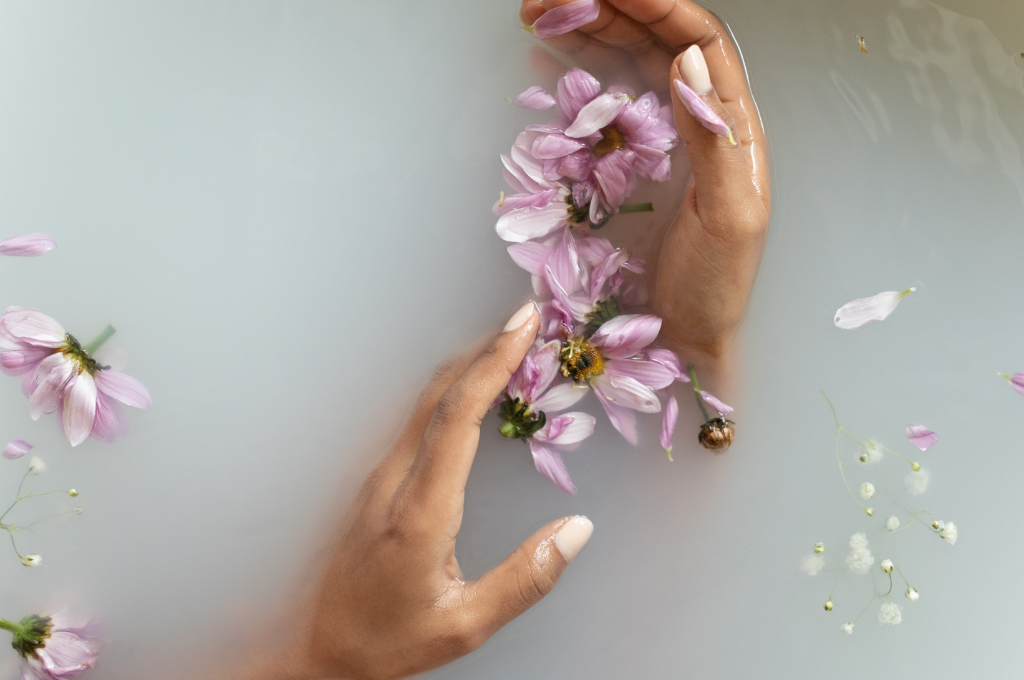 manos en una bañera con flores lilas